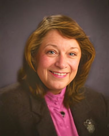 A woman with long hair wearing a pink shirt.