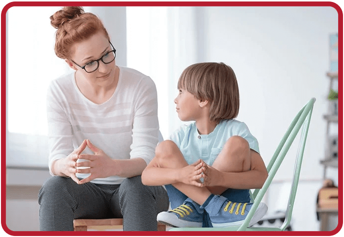 A woman and child sitting on the ground talking.