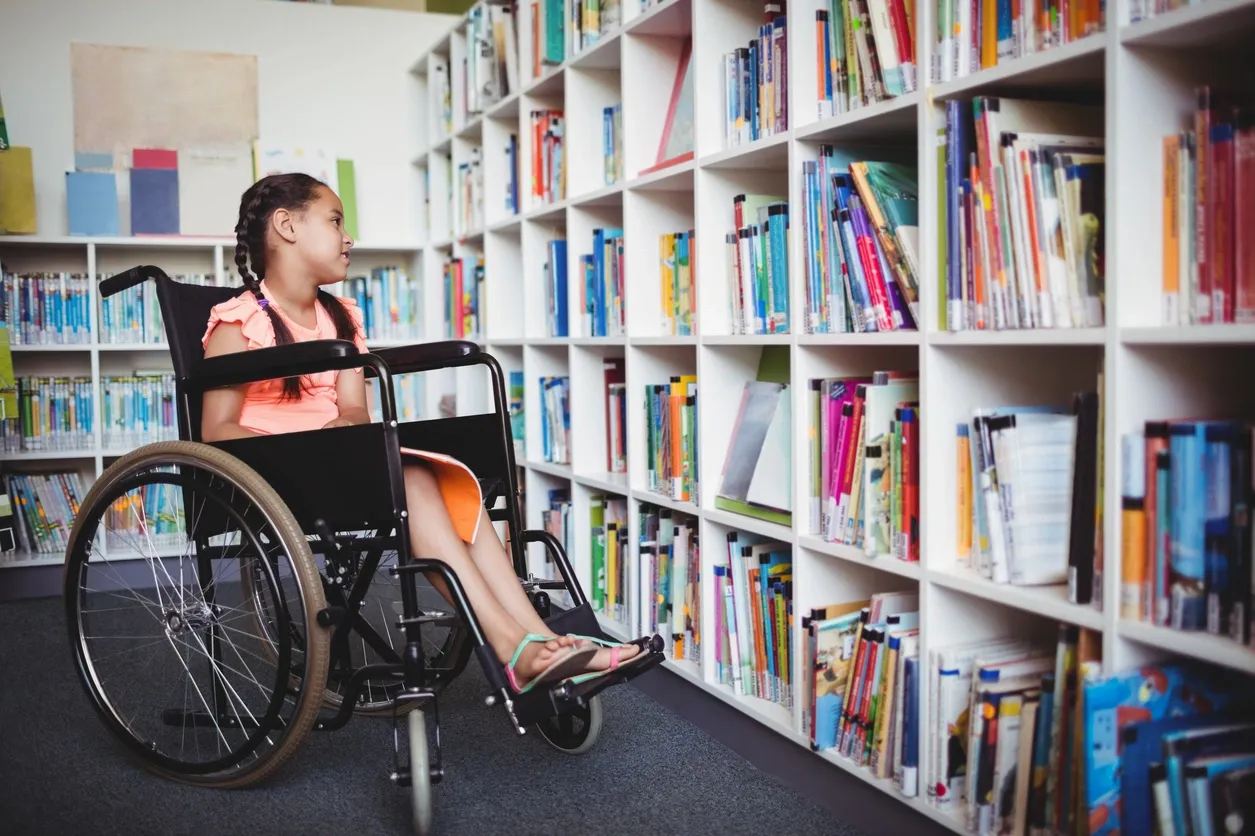 A girl in a wheelchair is sitting on the floor