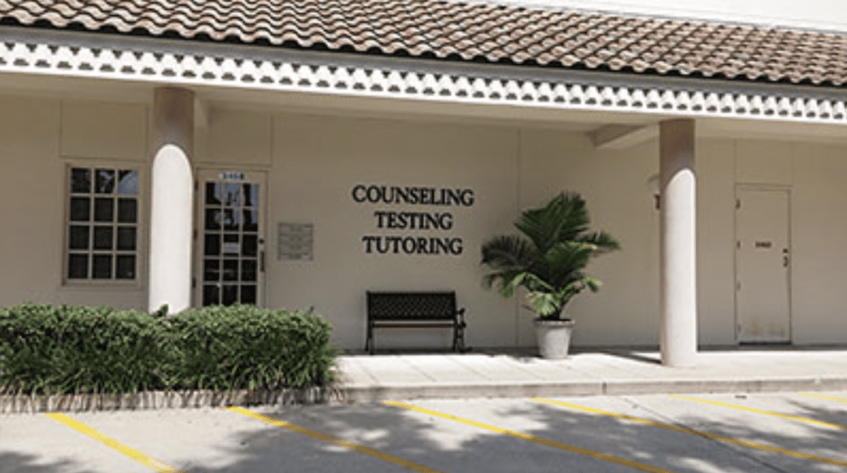 A building with a bench and sign on the front.