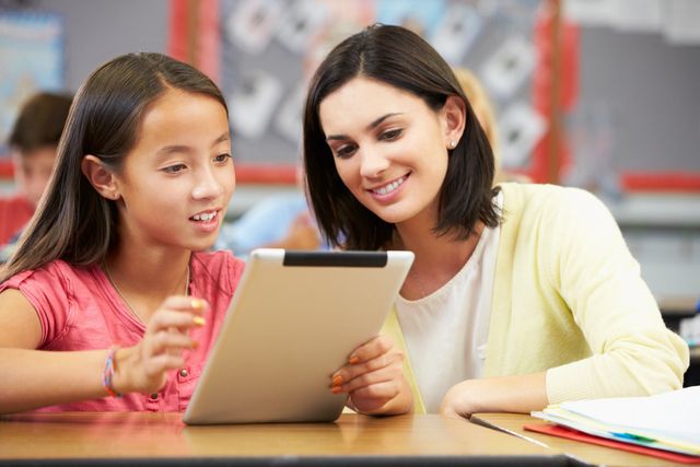 A woman and girl looking at an ipad.