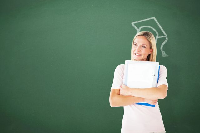 A woman holding a book in front of a chalkboard.